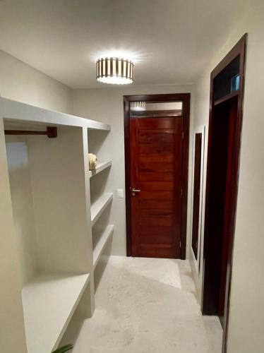 a hallway with a brown door and a room with shelves at Ronco do Mar Cumbuco in Cumbuco