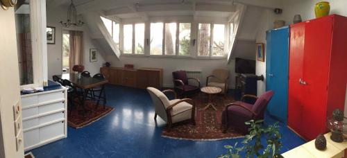 una sala de estar con suelos azules y una habitación con sillas en Gîte La Petite Maison, en Étretat