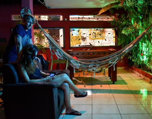 a woman sitting in a hammock next to a piano at Leo's Clan Beach Hostel in Paraty