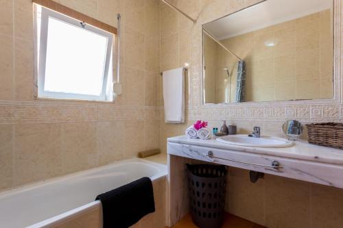 La salle de bains est pourvue d'un lavabo, d'une baignoire et d'un miroir. dans l'établissement CoolHouses Algarve, Casa das Amendoeiras, V4 Praia da Luz, à Luz