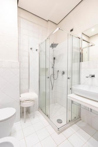 a white bathroom with a shower and a sink at Grand Hotel De Rose in Scalea