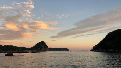 a view of a body of water at sunset at Guesthouse All you need - All rooms have an ocean view! in Shimoda