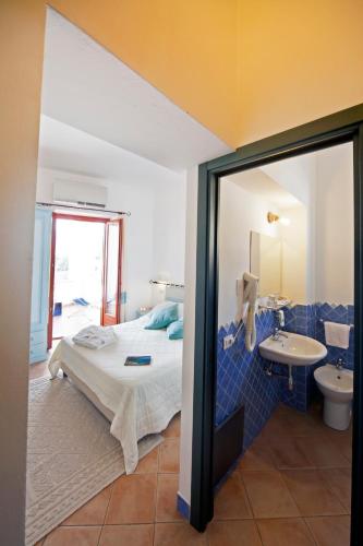 a bedroom with a bed and a bathroom with a sink at BUE MARINO Hotel & Roof Lounge in Cala Gonone