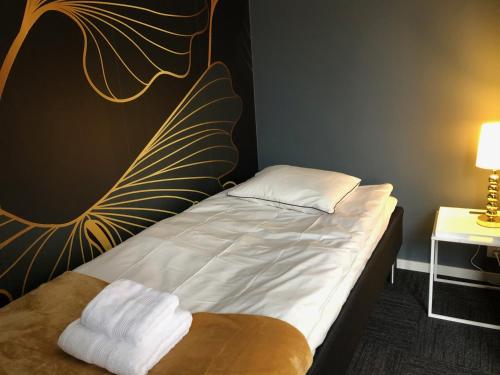 a bedroom with a bed with white sheets and a pillow at Mini-Hotel Borås Regementet in Borås