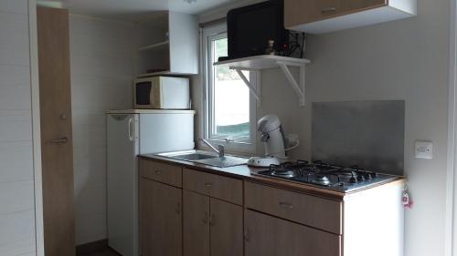 La cuisine est équipée d'une cuisinière, d'un évier et d'un réfrigérateur. dans l'établissement Mobilhome chez Cathy & Simon, à Marseillan