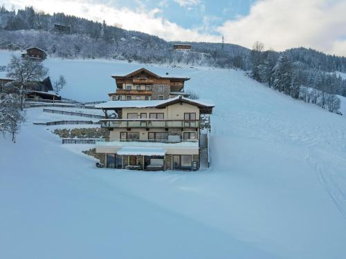 a building on a snow covered hill with snow at Chalets & Apartments Wachterhof in Kaltenbach