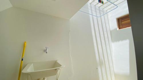 a white bathroom with a sink and a window at Condomínio Villa dos Corais in Maragogi