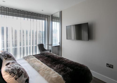 a bedroom with a bed and a flat screen tv at Custom House Apartments in Newry