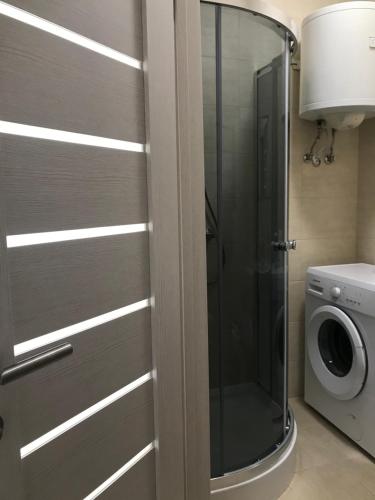 a glass shower door in a bathroom with a washing machine at Apartment for a pleasant stay in Odesa