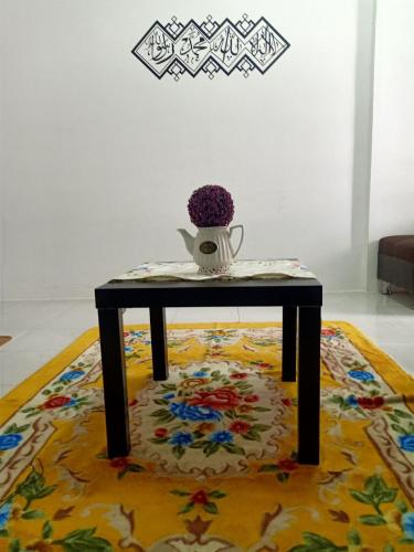 a table with a vase on top of a rug at Homestay Musafir Apartment Seri Iskandar 2.0 in Seri Iskandar
