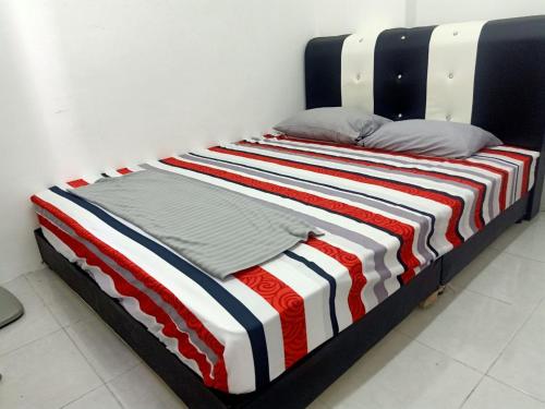 a bed with a red white and blue striped blanket at Homestay Musafir Apartment Seri Iskandar 2.0 in Seri Iskandar