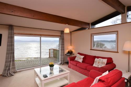 a living room with a red couch and a large window at Oystershell Lodge in Otter Ferry