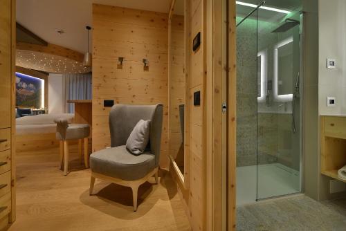 een badkamer met een stoel en een douche bij Kristiania Pure Nature Hotel & Spa in Cogolo