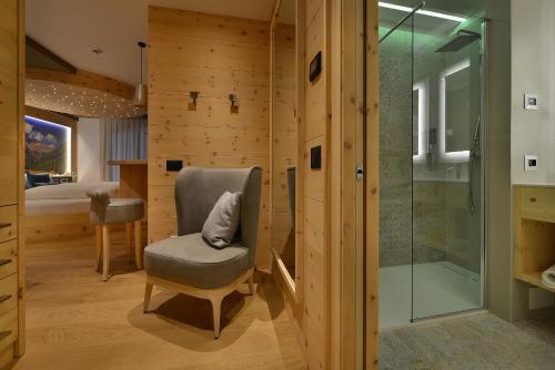 a bathroom with a chair and a shower at Kristiania Pure Nature Hotel & Spa in Cogolo