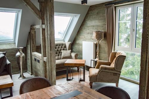 a living room with a table and chairs and windows at StrandBerg's Ursprung: Spa & Kitchen in Braunlage