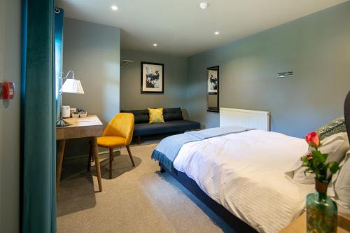 1 dormitorio con cama, escritorio y sofá en The Cowdray Arms, en Haywards Heath