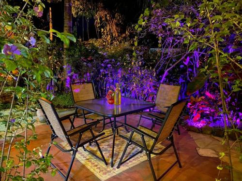 a table and chairs in a garden with purple flowers at Vila Pequeá Pousada Ilhabela in Ilhabela
