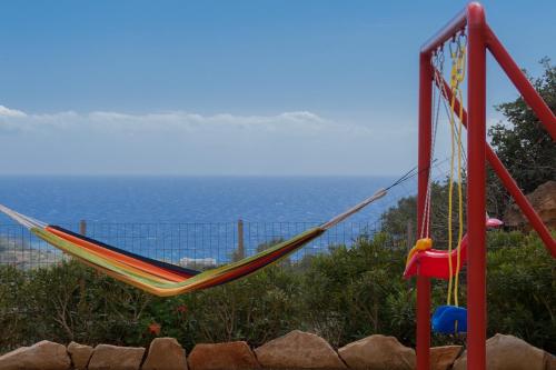 a hammock on a playground with the ocean in the background at Triopetra Luxury Villas Fournou Lago in Triopetra