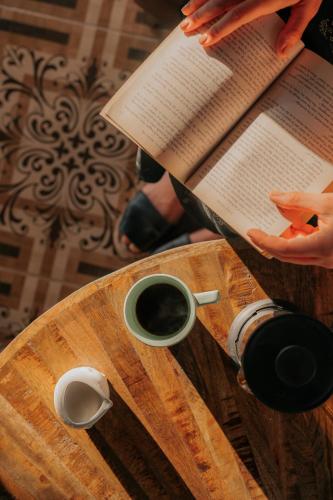 a person reading a book and a cup of coffee on a table at Hotel Boutique Casa Sánchez in Santo Domingo