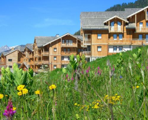 an apartment building with a field of flowers at Résidence Club mmv Le Hameau des Airelles **** in Montgenèvre