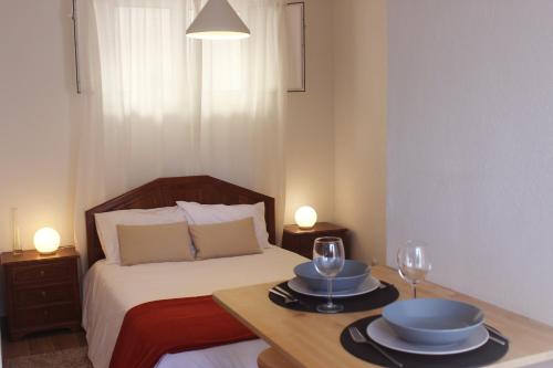 a bedroom with a bed with two plates and wine glasses at Casas d'Almofala in Vila de Rei