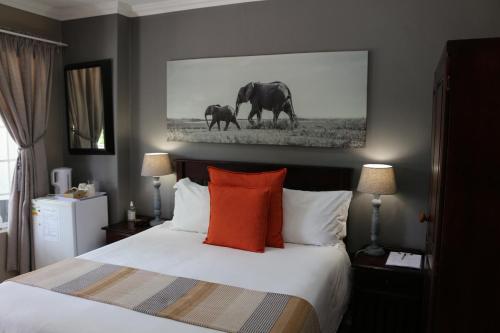 a bedroom with a bed with two elephants on the wall at Hummingbird's Nest in Nelspruit
