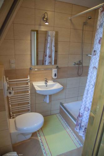 a bathroom with a sink and a toilet and a tub at Karczma Bełty in Glinno