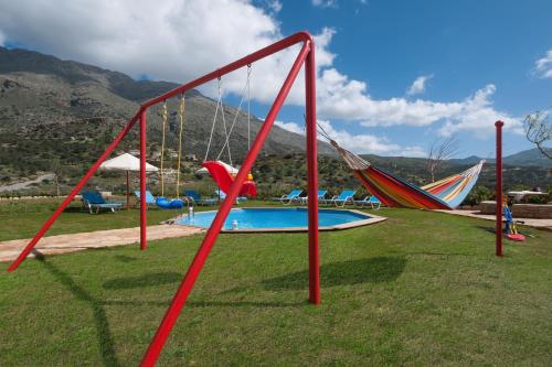 a group of swings in a field of grass at Triopetra Luxury Villas Fournou Lago in Triopetra