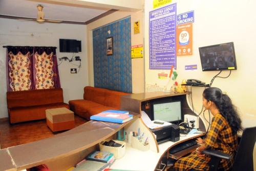 a woman sitting in front of a computer in a room at Shwetha Lodge in Kollūru