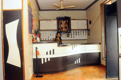 a woman standing behind a counter in a restaurant at Shwetha Lodge in Kollūru