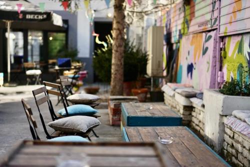 an outdoor patio with wooden tables and chairs with pillows at Good People Design Hostel in Belgrade