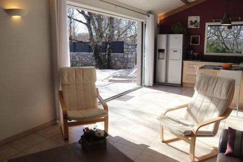 Il comprend un salon avec deux chaises et une cuisine. dans l'établissement Les Oliviers gîte grand confort au calme classé 3 étoiles, à Balazuc