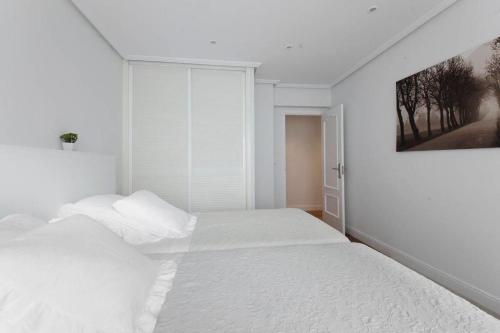 サン・セバスティアンにあるONDARRETA ROOM with independent entranceの白いベッドルーム(ベッド1台付)が備わります。壁には絵画が飾られています。