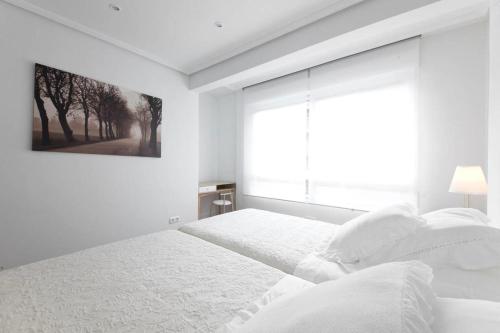 a white bedroom with a bed and a window at ONDARRETA ROOM with independent entrance in San Sebastián