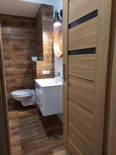 łazienka z toaletą i drewnianymi drzwiami w obiekcie Apartamenty Lawendowy Zakątek 5 w mieście Opole