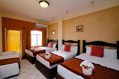 a hotel room with three beds with flowers on them at Hotel Quinta Maya in Flores