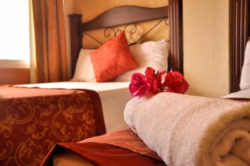 a hotel room with a bed with a red flower on it at Hotel Quinta Maya in Flores