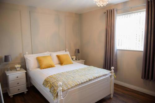 Un dormitorio con una cama con almohadas amarillas y una ventana en The Chalet town centre en Dungloe