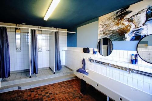 a bathroom with a shower and a sink and mirrors at Jugendherberge Hörnum in Hörnum