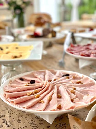 a plate of ham on a table with other foods at Hotel Zentiva Pinamar in Pinamar