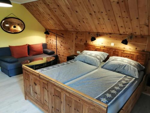 Cama grande de madera en habitación con sofá en Landhaus Gritschacher, en Sankt Peter in Holz