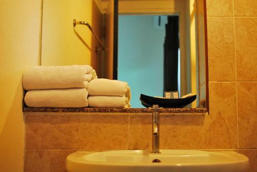 a bathroom with a sink and a mirror and towels at Grand Marina Residence Hotel in Ban Laem Chabang