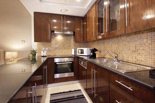 a kitchen with wooden cabinets and a sink at Prime Retreats - Downtown Dubai in Dubai