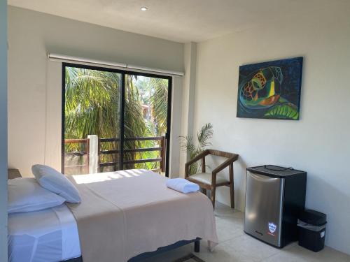 a bedroom with a bed and a tv and a window at Cuxos Hotel Beachfront in Isla Mujeres