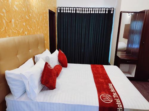 a bedroom with a bed with red and white pillows at Hotel The Holiday in Lahore