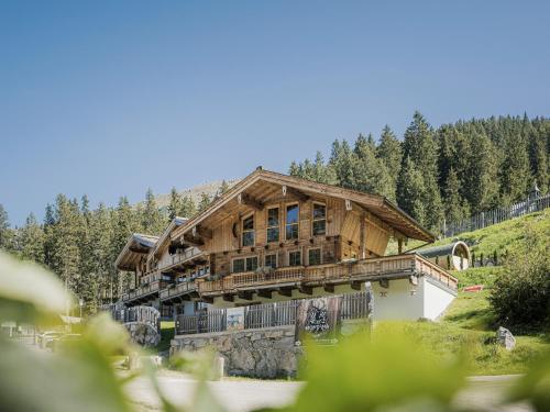 una gran casa de madera en una colina con árboles en Appart & Chalet Montana Hochfügen (Contactless Stay) en Hochfugen