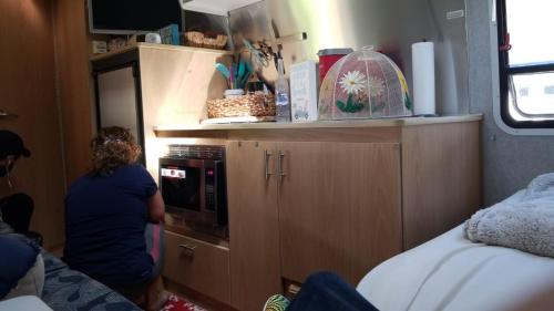 a woman standing in a kitchen with a microwave at Airstream in the Center of it All in Miami