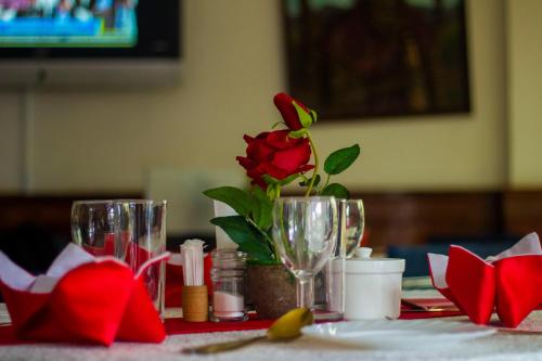 a table with a rose in a vase on it at New Hotel Aquiline in Arusha