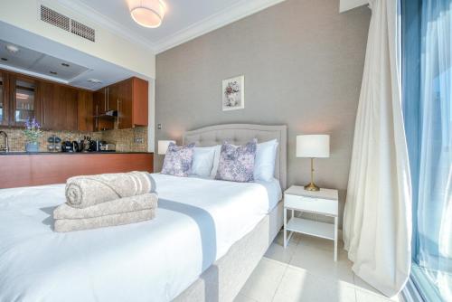 a bedroom with a large white bed and a kitchen at Prime Retreats - Downtown Dubai in Dubai