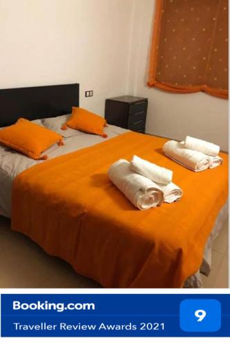 two towels on top of a bed with orange sheets at Apartament Comarques Catalanes in Móra d'Ebre